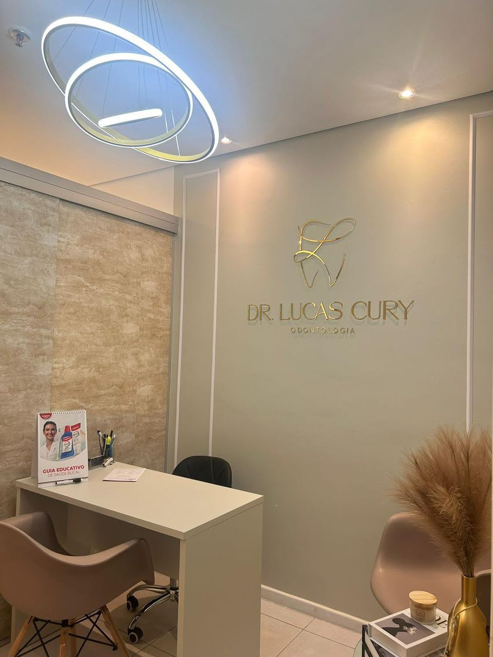 Recepção com a marca Dr. Lucas Cury na parede e iluminação circular.