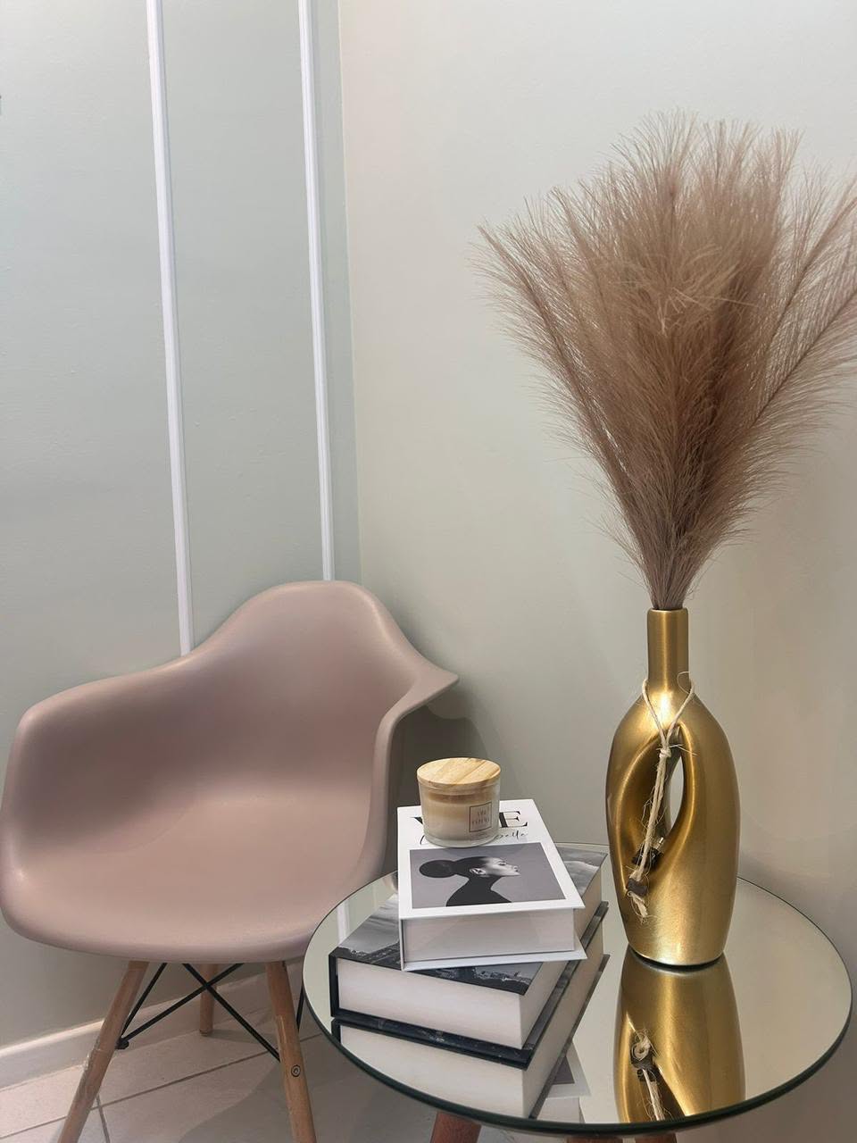 Cadeira da recepção ao lado de mesa com livros e vaso dourado.