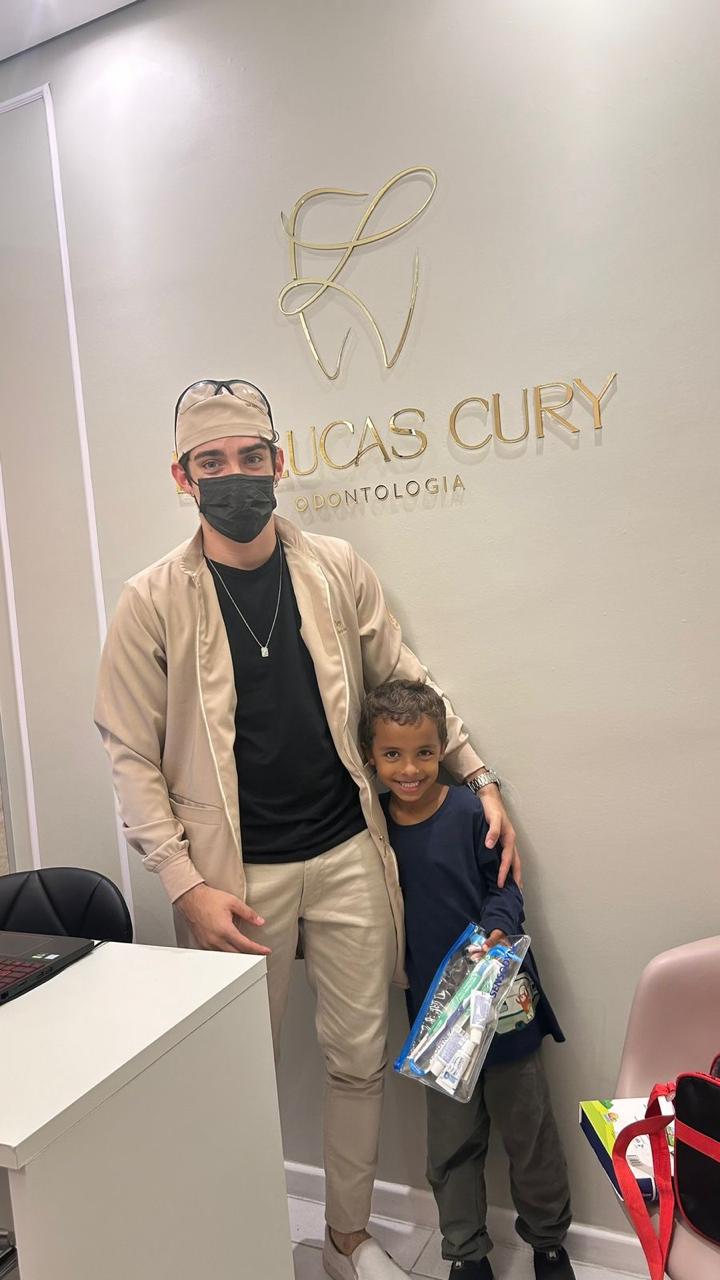Dr. Lucas Cury ao lado de uma criança no consultório.